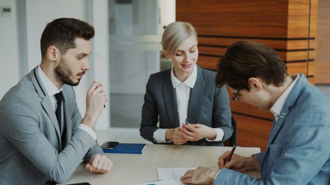 Business people signing a contract at a table